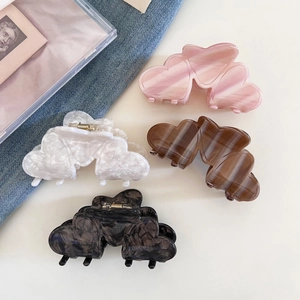 Close-up of heart-shaped acetate hair claws in pink, white, and marble textures