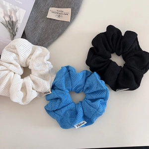 Gros plan de chouchous en maille en blanc, bleu ciel et noir avec étiquette tissée