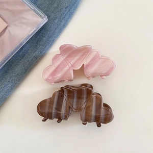 Close-up of heart-shaped acetate hair claws with marble texture in pink and brown