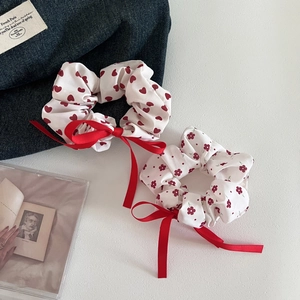 Close-up of white scrunchies with red heart and floral prints and silky ribbon bows
