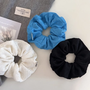 Trois chouchous en maille surdimensionnés en bleu, blanc et noir avec texture ajourée