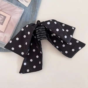 Detail view of a black and white polka dot ribbon bow hair claw clip for elegant styling