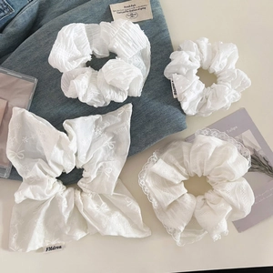 Détails de chouchous blancs avec dentelle, broderie et textures plissées