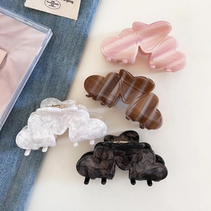 Flat lay of marble texture heart-shaped hair claw clips in pink, white, brown and black