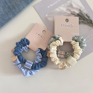 Detailed view of elastic hair scrunchies with square charms and metal tags on paper cards