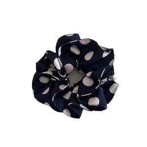 Navy blue polka dot scrunchie with soft fabric pleats for effortless bun hairstyles