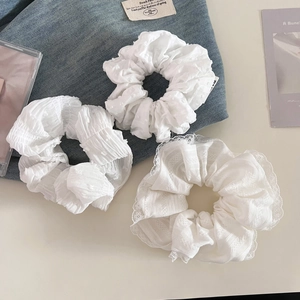 Détail de chouchous blancs montrant les textures de mousseline et de dentelle