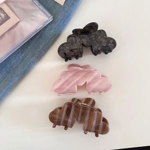 Three elegant French acetate hair claws in black, pink, and amber heart shapes