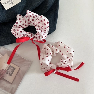 Floral and polka dot red scrunchies with ribbon bows on a textured background