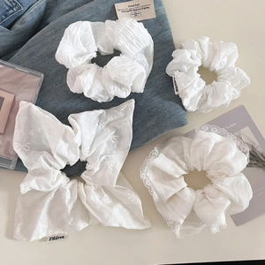 Détail de chouchous blancs et d'un grand nœud avec broderie délicate pour les cheveux