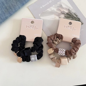 Detail of scrunchie set with resin cubes and metal tags on branded display card