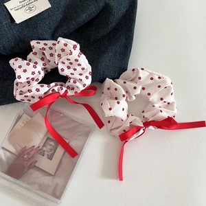 Detail view of red floral and polka dot scrunchies with long ribbon bows on denim background
