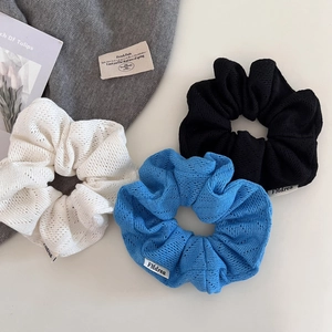 Détails de chouchous en maille ajourée tricolores : blanc cassé, bleu cobalt et noir