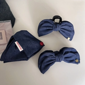 Detail of handmade dark blue denim bow hair clips with red button on fabric triangle