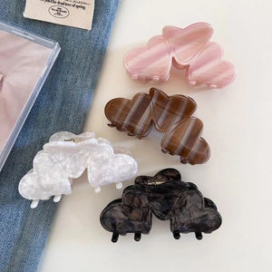 Detail view of heart-shaped hair claws in pink, brown, white and black colors