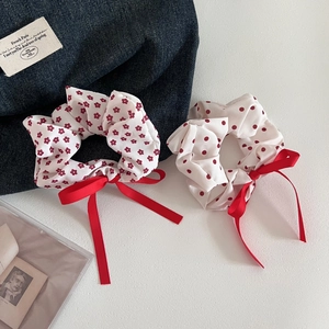Detail view of red floral and polka dot hair scrunchies with elegant ribbon bows