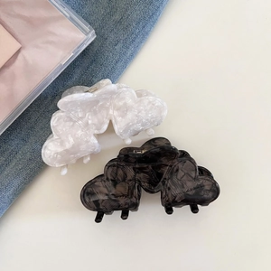 Detail view of heart-shaped hair claws with pearlescent and marble texture finish
