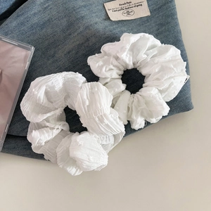 Lot de deux chouchous en mousseline blanche texturée sur fond en denim bleu foncé