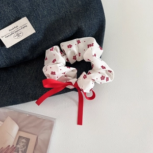 Close-up of white floral scrunchie with red polka dots and a bright red satin bow