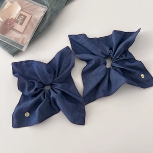 Close-up of vintage denim blue scrunchies with red stitching and gold metal brand tag