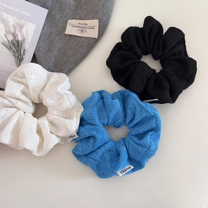 Détail de trois chouchous en maille bleue, noire et blanche avec des étiquettes tissées