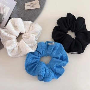 Vue macro détaillée de chouchous tricotés blancs, bleus et noirs en texture ajourée