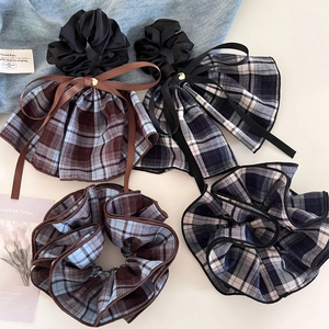 Detailed shot of retro plaid scrunchie with long ribbons and metal heart charm detail