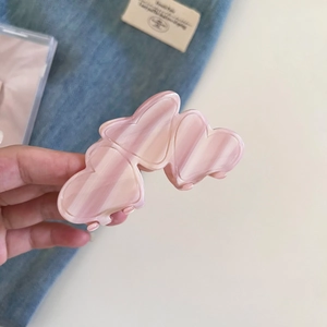 Detail of pink marble heart hair claw clip with acetate finish held by hand