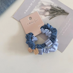 Close-up of blue scrunchies with square gold charms and textured fabric detail