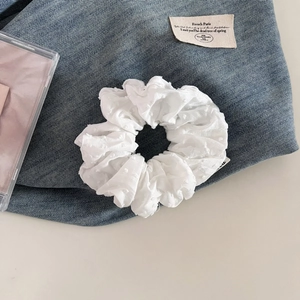 Détail d'un chouchou blanc avec texture jacquard à pois 3D et étiquette de marque