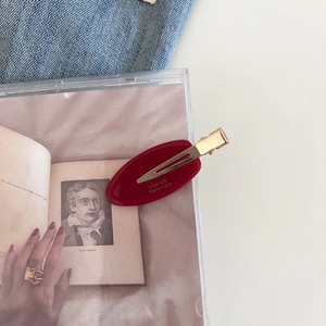 Close-up of burgundy acetate oval hair clip with gold metal and FRANCE Handmade text