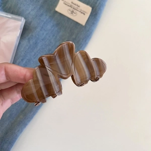Close-up of cloud-shaped hair claw clip with brown marble texture in high-gloss finish