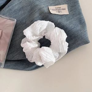 Gros plan d'un chouchou blanc avec texture plissée sur un fond en tissu denim