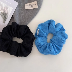 Détail de chouchous en maille ajourée bleue et noire avec étiquette sur fond blanc