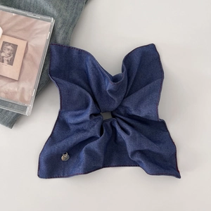 Oversized denim blue scrunchie with red stitching and silver tag for low ponytail styles
