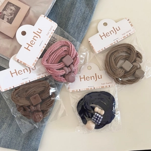 Detail of four high-elastic hair bands with plaid decorative buttons in premium packaging