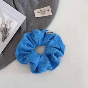 Gros plan détaillé sur la texture du chouchou en tricot bleu avec étiquette tissée