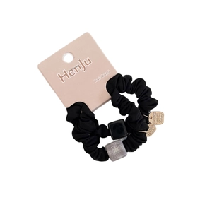 Set of two black scrunchies with square beads, floral accents, and gold labels