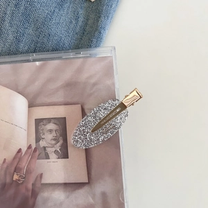 Detail of elegant gold alligator clip with sparkling oval glitter surface on artistic background