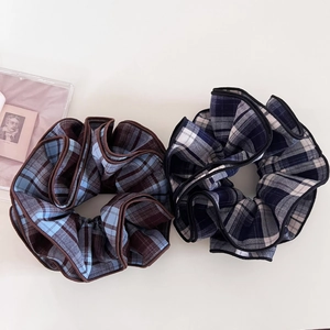 Detail of blue and brown plaid scrunchies with streamers on a clean cream background