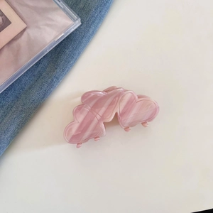 Detailed close-up of pink marbled acetate heart hair claw clip on a stylish desk