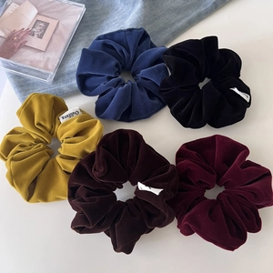 Close-up detail of five vintage velvet scrunchies in rich colors with premium texture