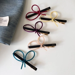 Detail of colorful acetate bow hair clips with gold metal base and handmade lettering