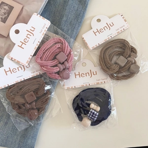 Close-up of four knitted elastic hair ties with matte plastic charms in a retail package