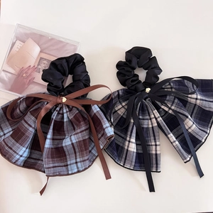 Detailed view of plaid bow hair ties with satin ribbons and small gold heart charms