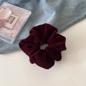 Detail shot of a vintage deep red velvet scrunchie on blue denim with soft lighting