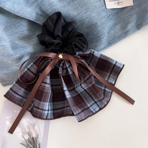 Detail of blue and brown plaid scrunchie with silk bow and gold heart charm