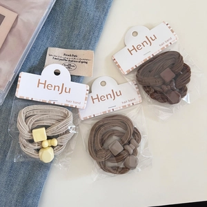 Detailed macro view of three elastic hair ties with cream-colored matte geometric charms
