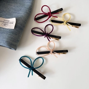 Detailed macro view of five colorful bow hair clips with acetate texture and gold logo