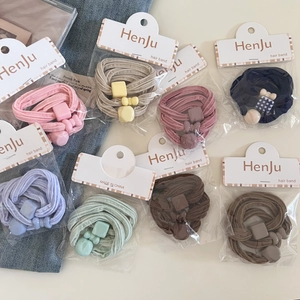 Close-up of elastic cream hair ties with resin geometric charms in assorted pastel colors